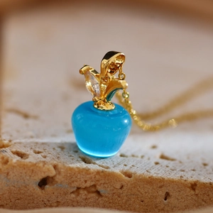 Détail macro du pendentif pomme en opale bleu ciel avec feuille dorée et zircon brillant