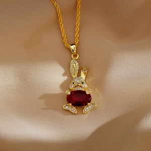 Detail van een gouden konijn-hanger met een rode edelsteen en ingelegde zirkonia-kristallen
