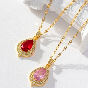 Elegant water drop pendants with red and pink stones on gold chains and white pillars