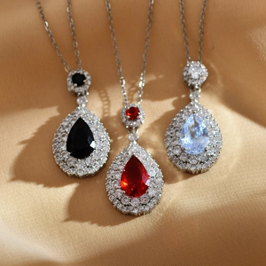Detailed close-up of pear-cut emerald and ruby pendants with cubic zirconia on silk