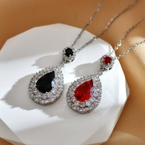 Detailed view of teardrop pendant necklaces with red and black stones on silk