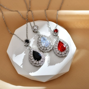 Pear-cut pendant necklaces with colored gemstones and silver chain on silk backdrop