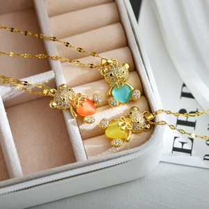 Tres collares de osito dorado con circonitas de colores en forma de corazón en joyero