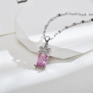 Elegante strik en bloem hanger ketting met roze zirkoon en zilveren afwerking op wit deco