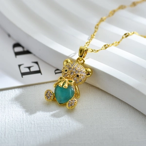 Detalle de colgante de oso dorado con circonitas micro-pavé y gema de corazón turquesa