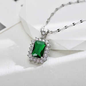 Luxurious emerald-cut green zircon necklace with halo diamond setting on white marble