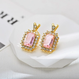 Close-up of elegant gold earrings with rectangular pink zircon and halo diamonds