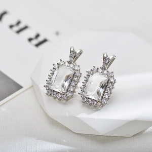 Detailed macro view of halo-set rectangular zircon stud earrings with silver plating