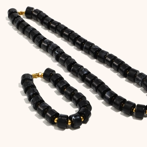 Macro detail of black marble acrylic cylinder necklace and bracelet with gold accents
