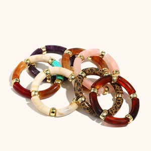 Close-up of stacked colorful acrylic tube beads bracelets with gold metal spacers