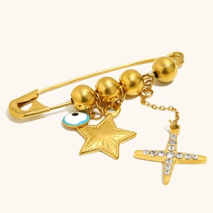 Detail of 18K gold-plated pin brooch featuring evil eye charm and rhinestone star charms