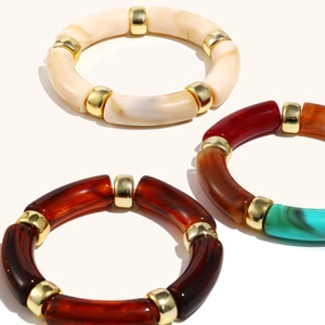 Detail of three stretch beaded bracelets featuring resin marble patterns and gold spacers