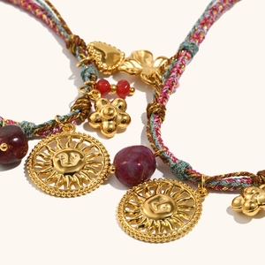 Macro detail of bohemian braided rope necklace with sun mask and heart gold pendants