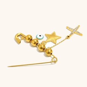 Detail of 18K gold-plated safety pin brooch with evil eye, star and cross charms