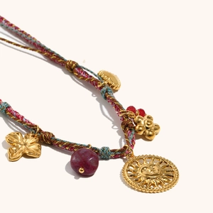 Close-up of bohemian woven cord necklace with sun face pendant and purple bead detail