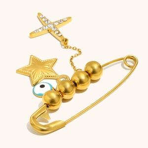 Detail of 18K gold-plated safety pin brooch with evil eye and star charms