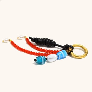 Detail of beaded keychain with red crystals, blue glass beads, and gold spring clasp