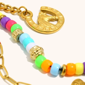 Detail of colorful beads and gold horseshoe pendant with embossed horse head icon