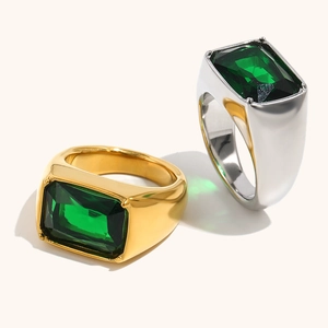 Macro detail of emerald-cut green gemstones on gold and silver wide signet rings