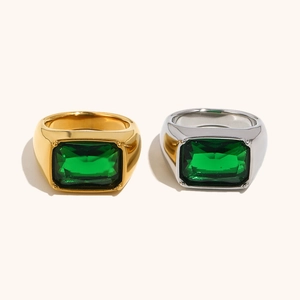 Detailed view of gold and silver rings with emerald green rectangular gemstones