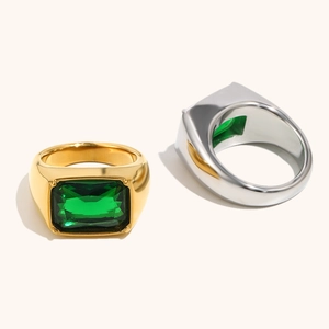 Macro shot of gold and silver signet rings featuring rectangular emerald-cut green gems