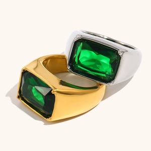 Gold and silver wide band signet rings with emerald cut green gemstones in glossy finish