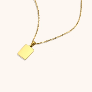 Détail macro du pendentif rectangulaire doré poli sur un collier fin en acier inoxydable