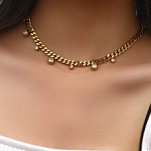 Close-up of golden Cuban chain necklace with six sparkling round zircon pendants on neck