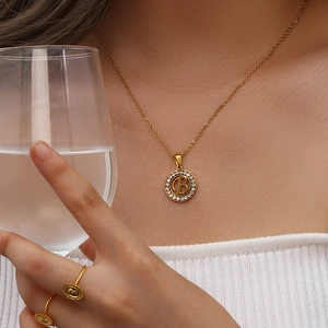 Detailaufnahme einer goldenen Halskette mit Zirkonia-Buchstabe B Anhänger an einem Model