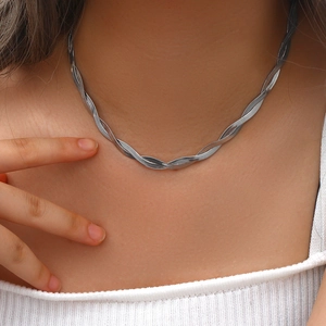 Close-up of twisted silver braided snake chain necklace on neck with polished metal texture