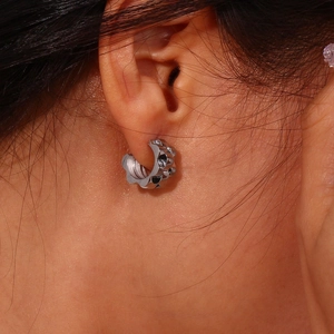 Macro shot of silver watchband texture hoop earrings in punk style stainless steel