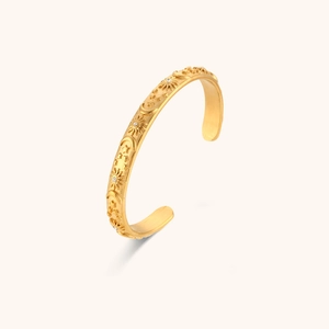Macro view of gold-plated celestial cuff bracelet with star and sun engravings
