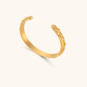 Close-up of 18K gold-plated bangle featuring embossed sun, moon and star motifs