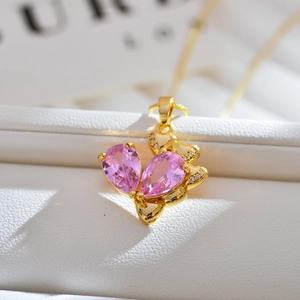 Detalle macro del colgante dorado con circonitas rosas sobre soporte de cuero blanco