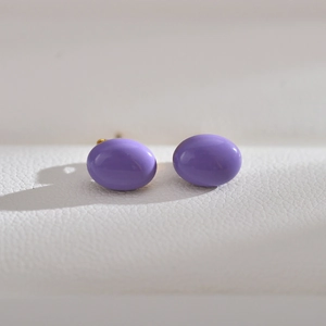 Macro view of purple oval stud earrings with a glossy finish and golden metal pins