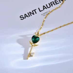 Luxe gouden sleutelketting met groene hart zirkoon, kroon en veer details