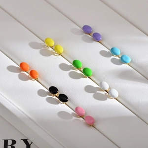 Macro view of colorful enamel stud earrings on a premium white leather display