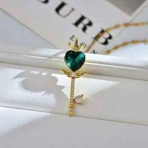 Detail van gouden sleutelketting met groen hartvormig kristal en kroonontwerp