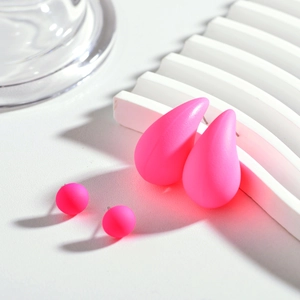 Vue détaillée d'un ensemble de boucles d'oreilles rose néon sur socle blanc