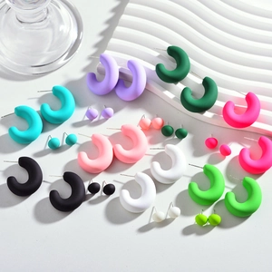 Gros plan de boucles d'oreilles créoles C en acrylique mat aux couleurs acidulées variées