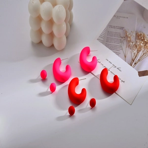 Détail de boucles d'oreilles créoles en acrylique mat rose et rouge avec clous assortis