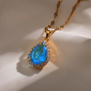 Detail van de peervormige blauwe kristallen hanger met een gouden schakelketting luxe