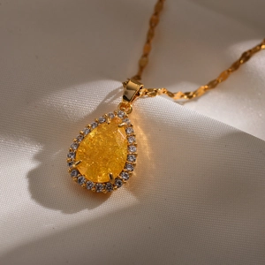 Detailweergave van druppelvormige gele kristallen hanger met zirkoon op gouden ketting