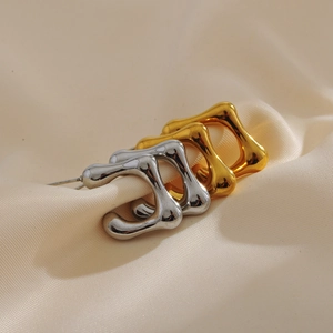 Detailansicht unregelmäßiger Lavade-Ohrringe in Gold und Silber auf beiger Seide