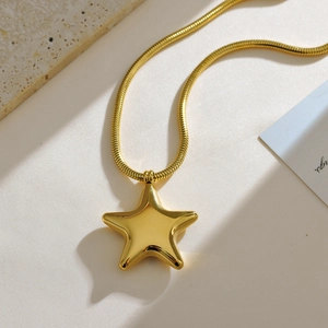 Detailopname van een gouden 3D sterhanger met gepolijste afwerking aan een slangenketting