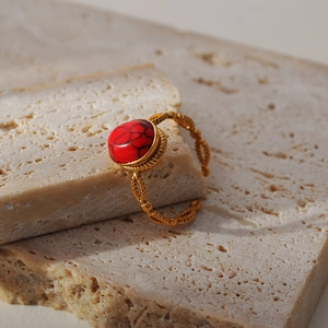 Vintage goudkleurige verstelbare ring met rode gemarmerde steen op travertijnsteen
