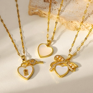 Colliers dorés avec pendentifs cadenas cœur, clé et nacre sur une surface en pierre