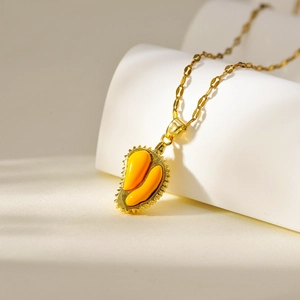 Gold plated durian pendant necklace with yellow enamel fruit core on white background