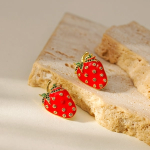 Detail of red strawberry earrings with gold plating and green zircon leaf accents