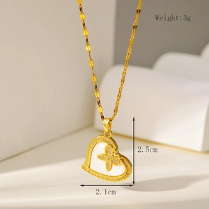Detail van gouden hartvormige ketting met micro-diamanten en wit schelp klaverblad motief